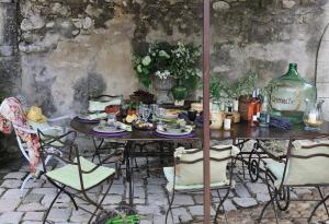 a table with plates of food on it with chairs at Villa Grenache, La Bastide de Marie, Villa avec services in Ménerbes