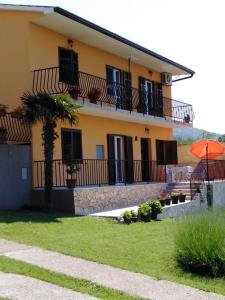 a yellow house with a balcony and an orange umbrella at Apartman Knapić in Koromačno
