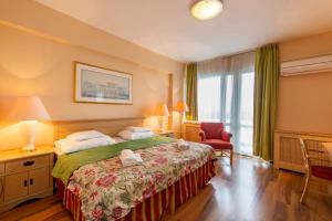 Hotel Fit Hévíz في هفيز: غرفه فندقيه بسرير ونافذه