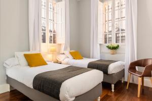 dwa łóżka w pokoju z dwoma oknami w obiekcie Imperial Luxury Apartment w Sewilli