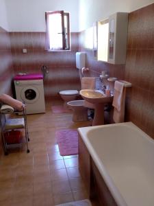 uma casa de banho com 3 WC, uma banheira e um lavatório. em Apartman Knapić em Koromacno