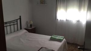 a bedroom with a bed with a white blanket and a window at TRUJILLO HOLIDAY HOME con PISCINA in Conil de la Frontera