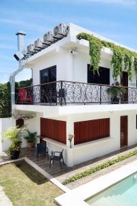 a white house with a balcony and a swimming pool at Red Panda Hostal in Playa del Carmen