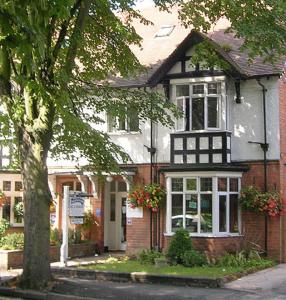 a house on a street with a tree in front of it at Salamander Guest House in Stratford-upon-Avon