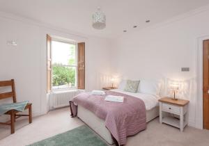 a white bedroom with a bed and a window at The Lochside House Residence in Edinburgh