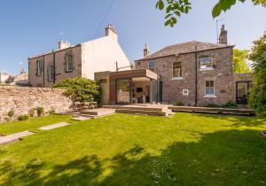 an old stone house with a lawn in front of it at The Lochside House Residence in Edinburgh