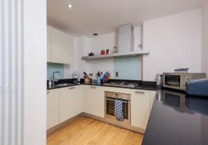 uma cozinha com armários brancos e um micro-ondas em The Quartermile Meadows View Residence em Edimburgo