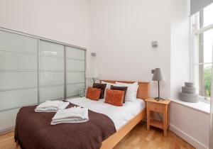um quarto branco com uma cama grande com almofadas laranja em The Quartermile Meadows View Residence em Edimburgo