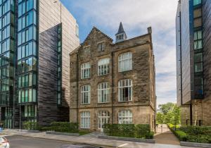 an old brick building in a city with tall buildings at The Quartermile Meadows View Residence in Edinburgh