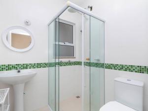 y baño con ducha, aseo y lavamanos. en Aluguel Casa 3 quartos p/ 12 pessoas | Bombas/SC, en Bombinhas