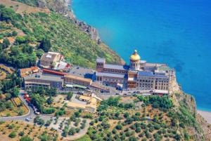 a building on a hill next to the ocean at Sea Elegance in Oliveri