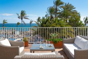a patio with chairs and a table and the ocean at VIK Hotel San Antonio in Puerto del Carmen