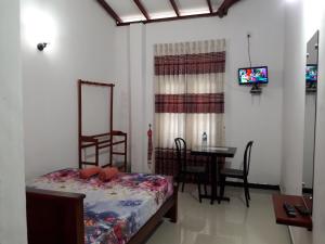 Attanagalla的住宿－White Wall Hotel，一间卧室配有一张床、一张桌子和一台电视