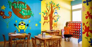 a dining room with tables and a wall covered in paintings at Maistra Select Funtana All Inclusive Resort in Funtana