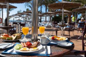 a table with plates of breakfast food and orange juice at VIK Hotel San Antonio in Puerto del Carmen