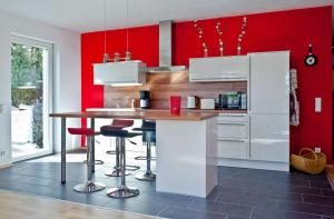 a kitchen with red walls and a counter with stools at Ferienwohnung Paula in Bitz