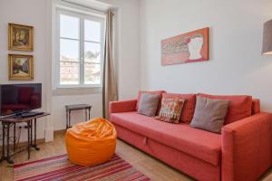 a living room with a red couch and a television at Alfama River View Tailor Made Flat in Lisbon