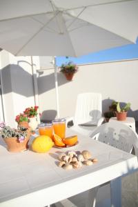 a white table with fruit and orange juice and an umbrella at APPARTAMENTO L'AIRONE in Balestrate