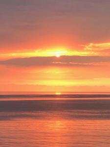 Elizabeth' Luxury Apartments في بوموري: غروب الشمس على المحيط مع الشمس في السماء