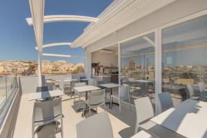 a balcony of a restaurant with tables and chairs at Dun Gorg Guest House in Marsaxlokk