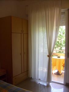 a bedroom with a bed and a window with a table at Hotel Tiziana in Rimini