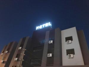 a building with a neon sign on top of it at Master Gold Hotel Express in Cascavel