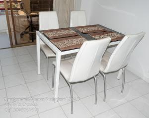una mesa de comedor con 4 sillas blancas alrededor en Condominio Nuevo Rodadero 1204, en Santa Marta