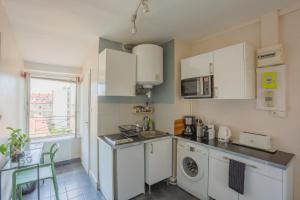a kitchen with white cabinets and a washer and dryer at Nid Cosy - Lyon 6e in Lyon