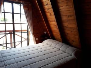 Bett in einem Zimmer mit einem großen Fenster in der Unterkunft La Ñata in Tornquist