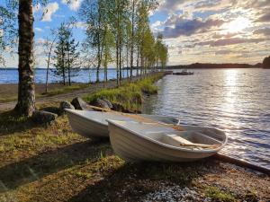 dois barcos sentados na margem de um lago em B&B Taipaleenniemi em Savonlinna