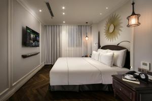 a bedroom with a large white bed and a desk at Canary Hotel in Hanoi