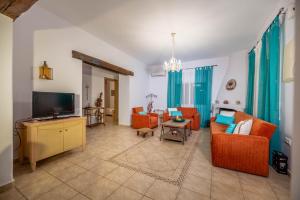 a living room with orange chairs and a flat screen tv at Ktima Argyrou Stegna in Archangelos