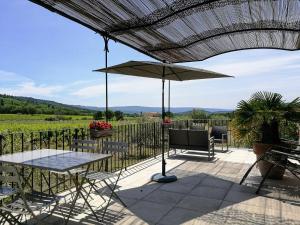 eine Terrasse mit einem Tisch und einem Sonnenschirm in der Unterkunft Les Petits Cléments in Villars