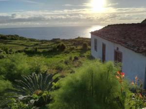 a house on a hill with the ocean in the background at Casa da Queijaria in Faja Grande