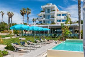 un hotel con sedie e ombrelloni accanto a una piscina di Acacia Palace a Marina di Ragusa