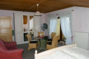 ein Wohnzimmer mit einem Tisch, Stühlen und einem Bett in der Unterkunft Pension Steiger in Bad Griesbach