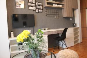 a living room with a tv and a table with flowers at Very central cozy apartment in Novi Sad