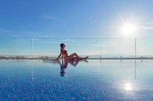 a woman sitting in the water in a swimming pool at H10 Vintage Salou - Adults Only in Salou