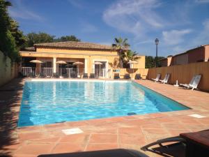 a swimming pool with chairs and a house at Résidence Lagrange Vacances Green Bastide in Roquebrune-sur-Argens