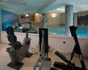 a gym with a swimming pool and exercise equipment at Sant Alphio Garden Hotel & SPA in Giardini Naxos