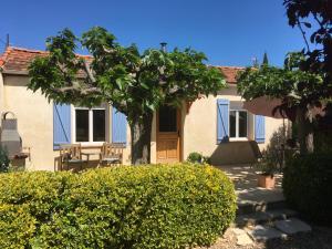 a house with a blue door and trees and bushes at Maison Oleander in Bize-Minervois