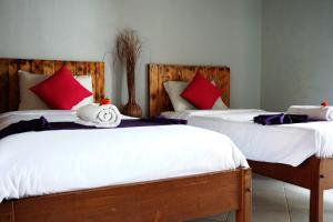 1 dormitorio con 2 camas y almohadas rojas y blancas en Louto Dmell Guesthouse, en Sanur