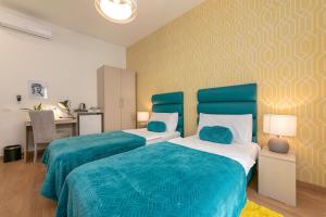 a bedroom with two beds with blue sheets and a desk at Preziosa in Pula