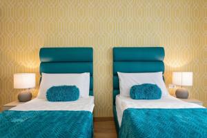 two beds with blue pillows on them in a room at Preziosa in Pula