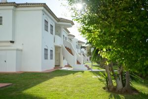 una fila de edificios blancos con árboles en el patio en LA BARROSA-NOVO SANCTI PETRI, wifi, aire acondicionado, parking, en Chiclana de la Frontera