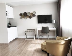 ein Wohnzimmer mit einem TV, einem Stuhl und einem Tisch in der Unterkunft TH39 Trend Hotel in Bad Vilbel