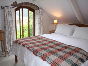 um quarto com uma cama com um cobertor xadrez em Church Barn em Harberton