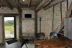 a room with a stone wall with a table and chairs at Le Moulin de la Motte Baudoin in Noyers-sur-Cher