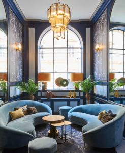 a lobby with blue couches and a chandelier at Hotel Konti Bordeaux by HappyCulture in Bordeaux