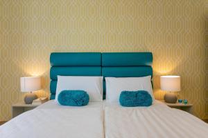 a bed with two blue pillows on it with two lamps at Preziosa in Pula
